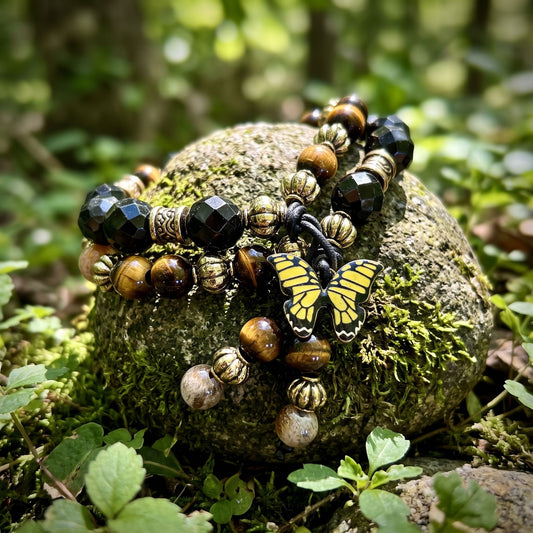 Natural outdoor shot of tiny Golden Tiger Eye Dual Crystal Energy bracelet over moss-covered stone surrounded by greenery, earthy and grounding.