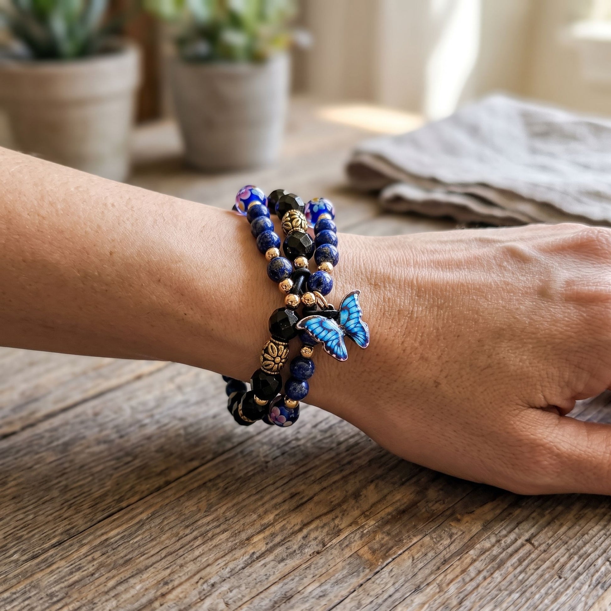 Full-body view of wrist wearing Blue Lapis Dual Crystal bracelet resting against a wooden table.